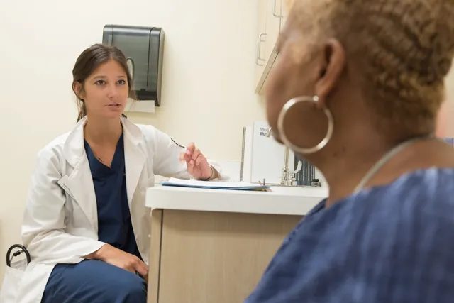 Female doctor in a white coat sitting and talking with an older woman patient in a clinic room
